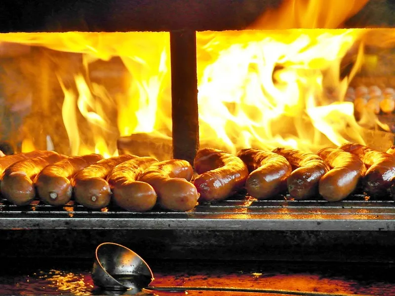 Bratwürste brutzeln über offener Flamme am Street-Food-Grill