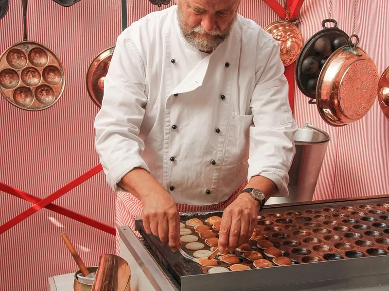 Koch bereitet kleine Pfannkuchen live an der Cooking-Station zu